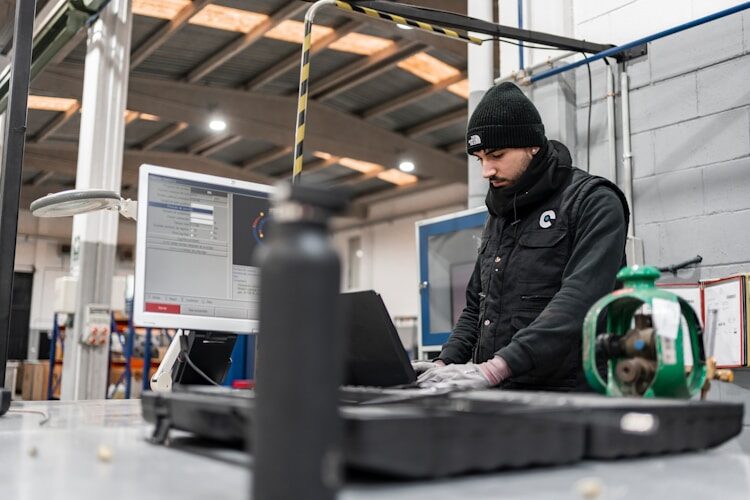 Man works on a computer in a manufacturing setting.